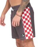 Boardshort Quiksilver de 16 pulgadas, color marrón con bandas laterales de diseño a cuadros rojos y blancos. Posee cintura fija con cordón de ajuste blanco y costuras visibles en contraste.