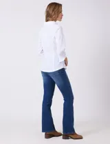 Camisa blanca entallada de algodón con escote en V y cuello con solapa. Presenta un diseño frontal con alforzas horizontales en la pechera y mangas tres cuartos con puños anchos rebatibles.