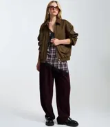 Campera de gamuza sintética color marrón, con cuello inglés, cierre frontal con botones metálicos, bolsillos delanteros y elástico en el bajo y puños.