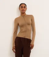 Campera deportiva Get Over para mujer, de corte ajustado, confeccionada en poliamida seamless con textura acanalada. Cuenta con cuello alto y cierre frontal con cremallera.