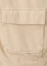 Chaqueta de algodón estilo denim, de diseño oversize, color beige, con cuello alto, manga larga, bolsillos de parche con solapa y cierre frontal de botones oscuros.