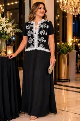 Vestido largo de seda color negro, de corte suelto y manga corta. Presenta un diseño con escote en V y un panel frontal decorado con tul bordado en color blanco y detalles de blonda.