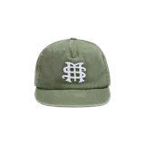 Gorro con visera plana de color verde militar, con efecto desgastado y bordado frontal en color blanco con las iniciales entrelazadas.