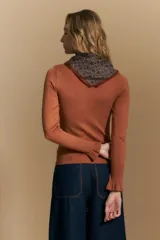 Polera de tejido fino color negro, con cuello alto y mangas largas con terminación sutilmente fruncida. Diseño ajustado al cuerpo.