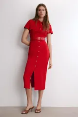 Vestido midi de color rojo, con cuello solapa, manga corta y cierre frontal de botones metálicos. Presenta bolsillos decorativos en el pecho y un cinturón a tono en la cintura.