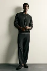 Pantalón regular fit de hombre color negro, confeccionado en tejido técnico ligero con cintura elástica, bolsillos frontales, bolsillos traseros de vivo y cierre frontal con cremallera y botón.