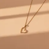 Conjunto de collar y dije en oro 18k. El collar presenta una cadena fina de eslabones y un dije en forma de corazón con incrustaciones de circonias.