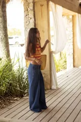 Pantalón wide leg de tiro medio confeccionado en denim, con cintura trabajada con pasacintas entrelazadas, cierre frontal y bolsillos laterales.