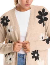 Cardigan de punto abierto con diseño jacquard de flores grandes en contraste. Presenta silueta holgada, hombros caídos y terminaciones en rib fino en puños y ruedo.