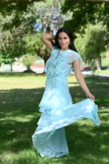 Vestido largo color beige, con escote en V, mangas cortas con volados y falda larga con volados en capas.