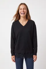 Buzo de punto negro, de corte holgado, con cuello en V y mangas largas.