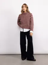 Sweater de punto con diseño de trenzas verticales, cuello alto y corte holgado. Presenta mangas largas con puños acanalados y un largo a la cadera.