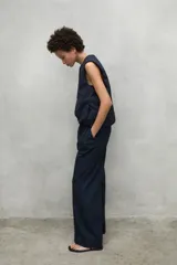 Pantalon de corte relajado y tiro alto, confeccionado en algodon, con pliegues frontales y bolsillos laterales.