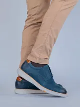Zapato de estilo casual tipo derby en color azul marino, confeccionado en cuero con detalles de perforaciones decorativas tipo brogue. Cuenta con cordones al tono, detalle en cuero color suela en el talón y suela de goma flexible color gris claro con tecnología de amortiguación.