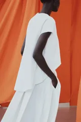 Camiseta blanca de algodón con cuello redondo, manga corta y diseño asimétrico de bajo redondeado y más largo en la espalda.
