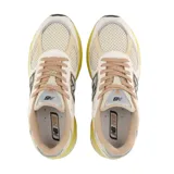 Championes urbanos New Balance modelo 2010, con diseño en tonos beige, crema y amarillo. Presenta una combinación de malla y gamuza en el exterior, con el logo N característico en el lateral y una suela de goma con entresuela amarilla destacada.