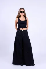 Jean de corte wide leg en color negro, con diseño de costuras curvas en la parte superior y pinzas que aportan volumen a la prenda. Presenta tiro medio, cierre frontal con botón y costuras en contraste.