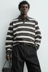 Polo de manga larga con diseño de rayas horizontales en tonos gris oscuro, negro y blanco marfil, cuello solapa y cierre frontal de botonadura oculta.
