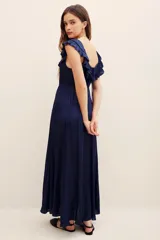 Vestido largo color azul marino con escote redondo, volados en el pecho y mangas cortas con volados. Cuenta con cordón ajustable en la cintura y falda larga fluida.