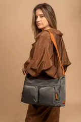Bandolera de tafeta impermeable, con dos compartimentos principales, dos bolsillos frontales con cierre y correa regulable con detalles en cuero sintético color suela.