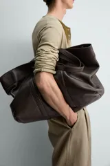 Bolso tipo shopper de piel en color negro, con diseño minimalista, doble asa de mano y compartimento principal con cierre magnético.