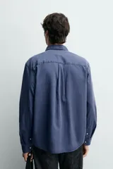 Camisa de corte regular fit en color azul, confeccionada en mezcla de lyocell y algodón, con cuello camisero, manga larga con puños abotonados, cierre frontal con botones y un bolsillo aplicado en el pecho.