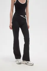 Calza flare de poliamida color negro, con diseño de tiro bajo y detalle de costura cruzada en la cintura.