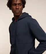 Buzo deportivo negro con capucha, cierre frontal con cremallera, bolsillos laterales y puños ajustados. Confeccionado en tejido de algodón y poliéster.