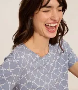 Blusa de pijama de viscosa con estampado de lacitos blancos sobre fondo azul. Presenta cuello redondo y mangas cortas, con un corte holgado y cómodo.