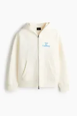 Campera con capucha H&M de felpa boxy en color beige, con cierre frontal, bolsillos tipo canguro y pequeño estampado azul en el pecho con la frase 'Not for Ceremony'.