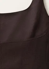 Vestido midi color borgoña de lino, con breteles anchos, escote cuadrado, corte recto, abertura frontal en el ruedo y detalle de costuras verticales.