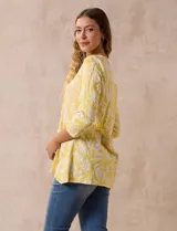 Blusa amarilla estampada con motivos florales en blanco, escote en V y mangas tres cuartos.