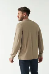 Remera de hombre negra de manga larga con puños, escote redondo y bolsillo en el pecho con etiqueta de marca.