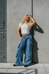 Pantalón estilo cargo parachute color blanco, de corte holgado, con cintura elástica y bolsillos laterales amplios con detalles de tiras y botones a presión.