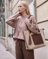 Cartera grande de cuero y gamuza, en tonos beige y chocolate, con asas largas para el hombro y bolsillo frontal con costuras artesanales.