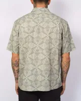 Camisa de manga corta color verde con estampado geométrico, cierre frontal con botones y un bolsillo en el pecho.