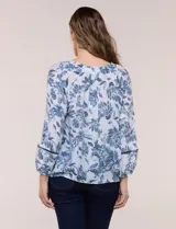 Blusa holgada de rayón y poliéster, marca Zac & Rachel, con estampado floral en tonos azules sobre fondo blanco. Posee escote en V con muesca central, mangas largas abullonadas con inserción de puntilla y puños elastizados.