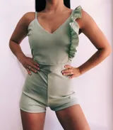 Mono corto blanco con escote en V, breteles finos y un volado en el hombro izquierdo.