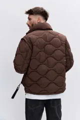 Cazadora acolchada de color azul marino con diseño de costuras onduladas, cierre frontal con cremallera y cuello alto. Presenta bolsillos frontales y un ajuste cómodo.