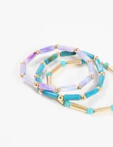 Pulsera elástica con mostacillas cilíndricas de plástico en tonos celeste, azul y lila, separadas por mostacillas doradas.