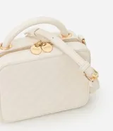 Bolso transversal tipo camera bag, color blanco con textura matelasse de rombos. Tiene correa fina ajustable y removible, cierre de cremallera y colgante de pompón.