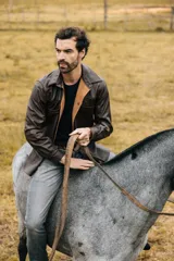 Campera de cuero marrón oscuro, con diseño clásico, cuello camisero, bolsillos frontales con solapa y cierre de botones a presión.