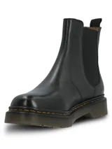 Botin estilo chelsea de cuero negro con paneles elásticos laterales, suela de goma dentada con costuras amarillas contrastantes y tirador trasero.