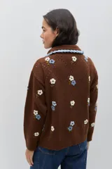 Saco de punto color bordó con bordados artesanales de flores en tonos rosados. Presenta un cuello con detalle de volados en color crema y cierre frontal con botones. De silueta amplia y cómoda.