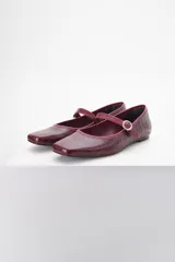 Ballerinas color borgoña con estampado croco, punta redondeada y tira sobre el empeine con hebilla metálica.