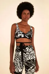 Top tejido con estampado tropical en blanco y negro. Tiene escote en pico cruzado, tirantes anchos y tiras para atar en la cintura.