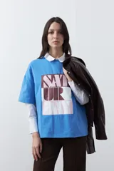 Remera de manga corta con corte boxy fit, color blanco, con estampa frontal geométrica en tonos azul, rosado y marrón.