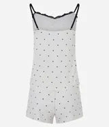 Conjunto de pijama compuesto por una musculosa de breteles finos ajustables con detalle de encaje negro en el escote y un short con cintura elástica. Ambas prendas presentan un estampado de lunares negros sobre fondo blanco.