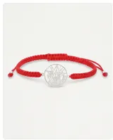 Pulsera de hilo rojo en macramé con dije central circular de plata 925 que presenta el símbolo del tetragramaton calado. Posee terminaciones con esferas de plata y sistema de ajuste regulable.