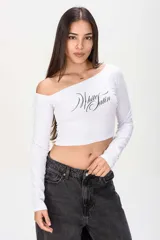 Remera crop blanca de manga larga, con escote asimétrico estilo off-shoulder y estampa frontal con la frase "White Satin" en letra cursiva negra.